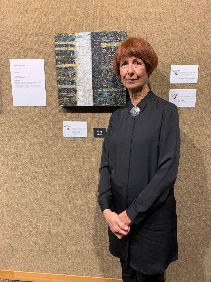 Diane Stapleton standing near her displayed abstract painting in Orlando Florida.